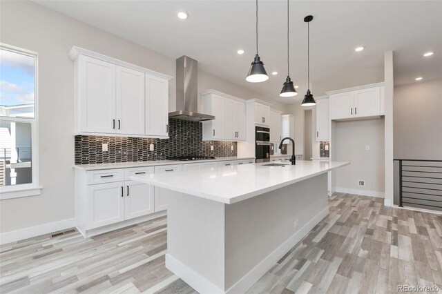 5835 Gianna Dr, Timnath, CO 80547 - kitchen featuring wall chimney exhaust hood, light wood finished floors, a sink, backsplash, and recessed lighting