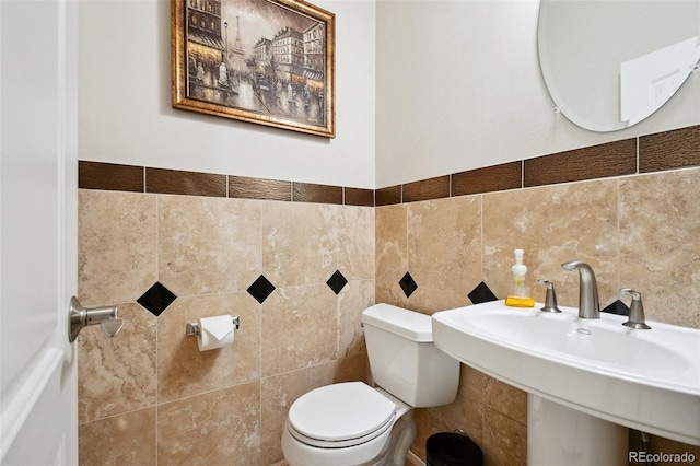 bathroom featuring tile walls, toilet, and sink