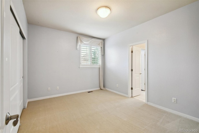 unfurnished bedroom with light colored carpet and a closet