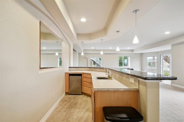 kitchen featuring decorative light fixtures, light colored carpet, sink, a tray ceiling, and kitchen peninsula