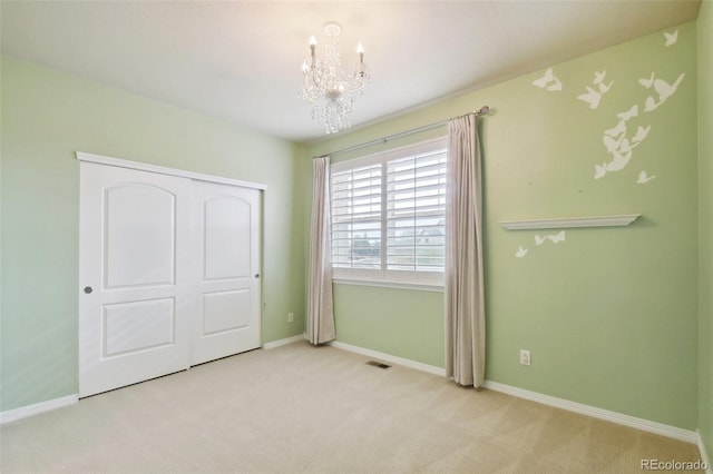 unfurnished bedroom featuring light carpet, an inviting chandelier, and a closet