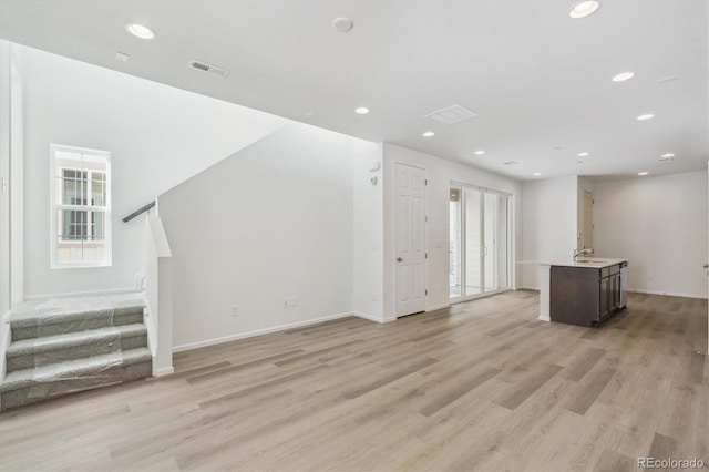 unfurnished living room featuring light hardwood / wood-style flooring and sink