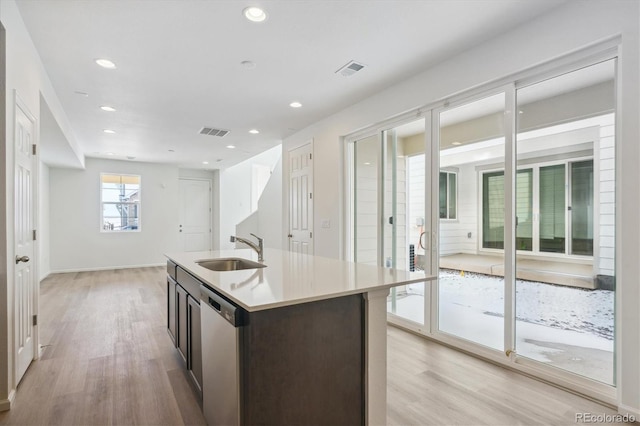 kitchen with dishwasher, a center island with sink, sink, light wood-type flooring, and dark brown cabinets