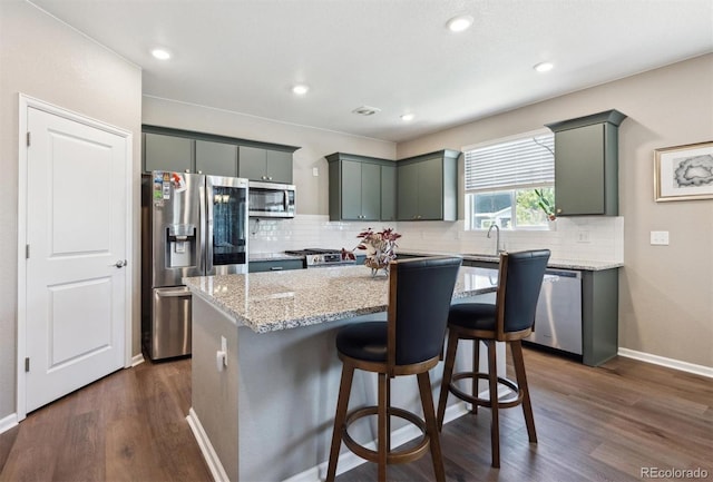 27130 E Maple Ave, Aurora, CO 80018 - kitchen featuring stainless steel appliances, dark wood finished floors, decorative backsplash, a kitchen island, and light stone countertops