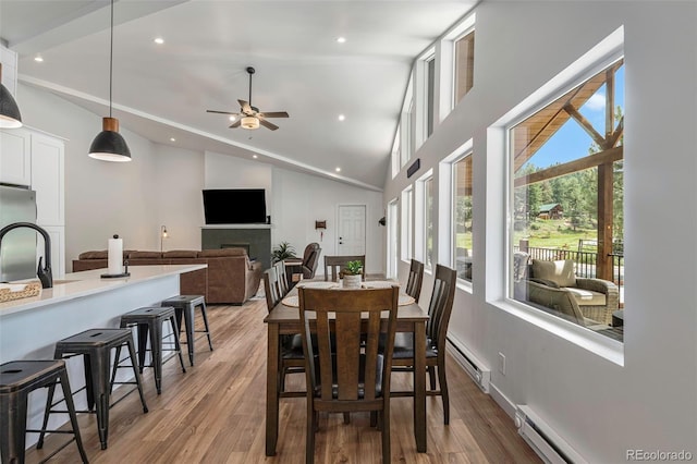 dining room featuring ceiling fan, wood-type flooring, high vaulted ceiling, and a baseboard heating unit