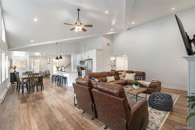 living room featuring light hardwood / wood-style flooring, high vaulted ceiling, ceiling fan, and sink