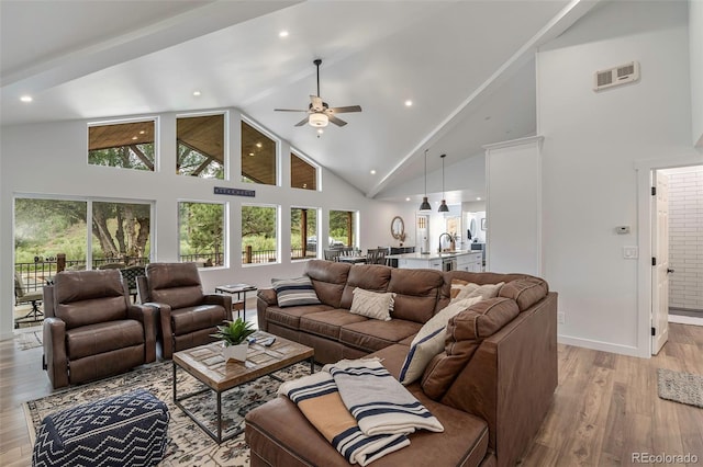 living room with ceiling fan, high vaulted ceiling, a healthy amount of sunlight, and light wood-type flooring