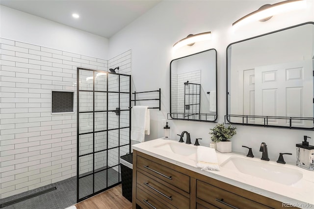 bathroom featuring tiled shower, wood-type flooring, and vanity