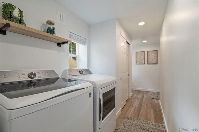 clothes washing area featuring washer and clothes dryer and hardwood / wood-style flooring