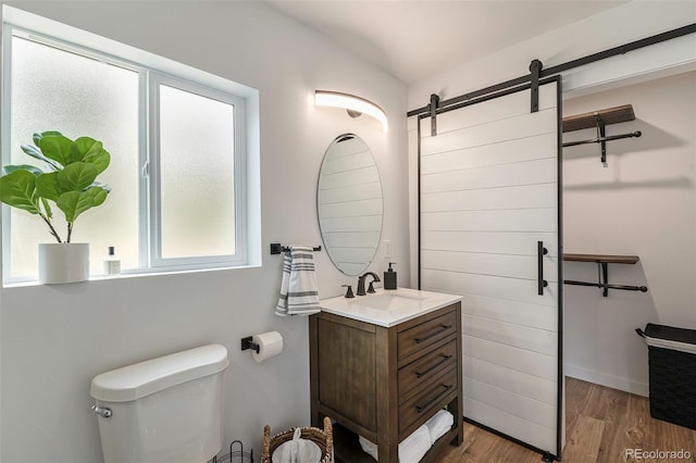 bathroom with hardwood / wood-style floors, plenty of natural light, toilet, and vanity