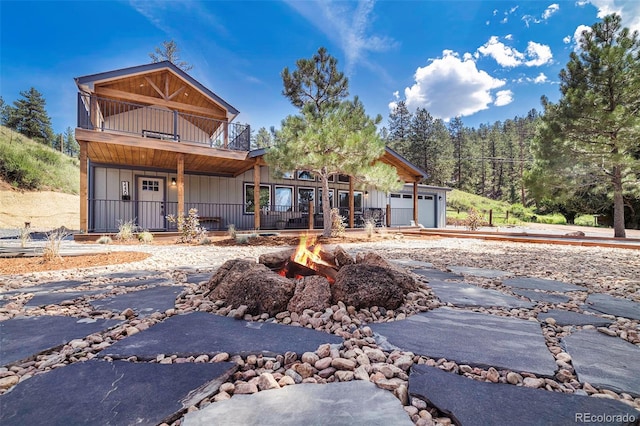 front of property with a balcony, a garage, and an outdoor fire pit