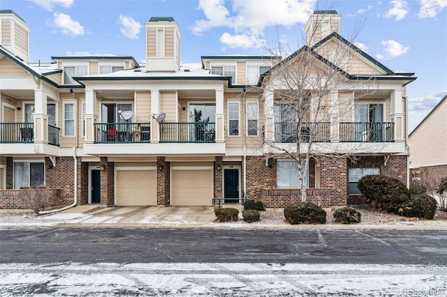 multi unit property featuring brick siding, driveway, a chimney, and an attached garage