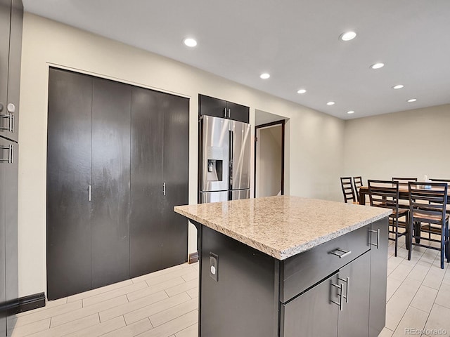 kitchen featuring stainless steel refrigerator with ice dispenser and a kitchen island