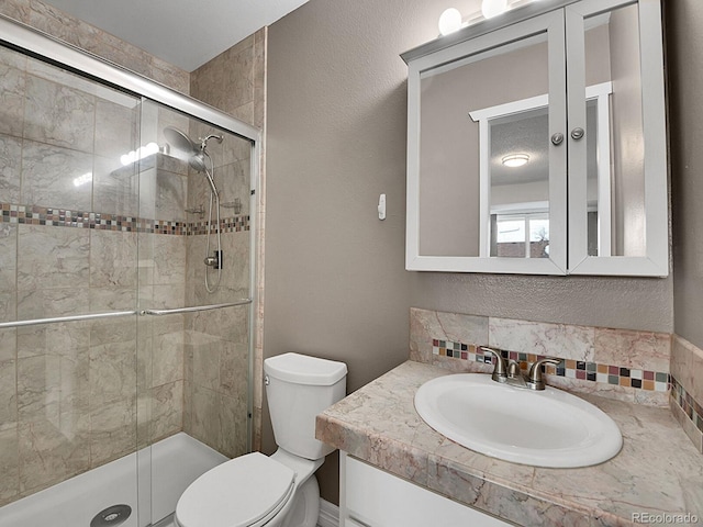 bathroom featuring an enclosed shower, backsplash, vanity, and toilet