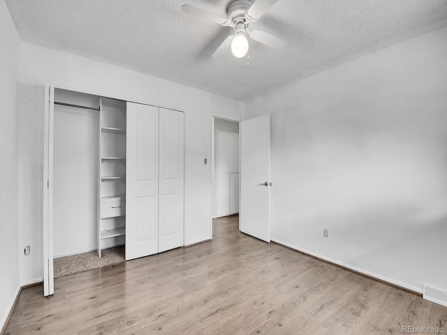 unfurnished bedroom with a textured ceiling, wood-type flooring, a closet, and ceiling fan