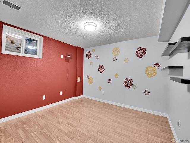 unfurnished room with light hardwood / wood-style floors and a textured ceiling