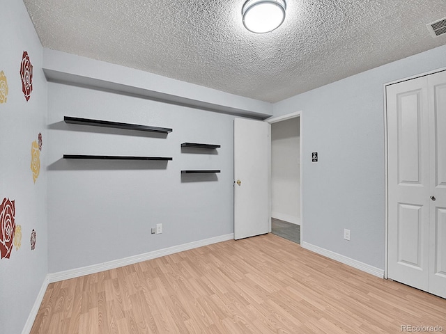 spare room with light hardwood / wood-style flooring and a textured ceiling