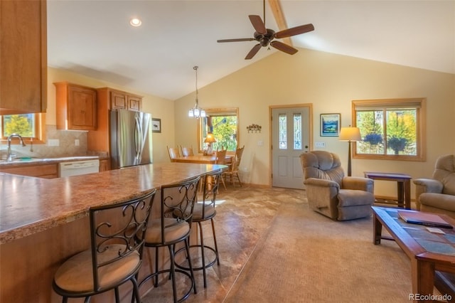 kitchen featuring sink, decorative light fixtures, stainless steel refrigerator, white dishwasher, and backsplash