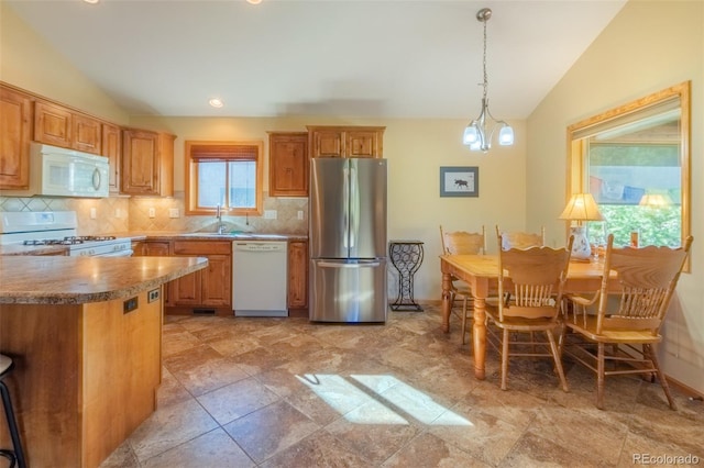 kitchen with tasteful backsplash, white appliances, vaulted ceiling, and decorative light fixtures