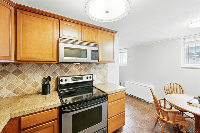 kitchen with electric stove, tile counters, backsplash, and brown cabinetry