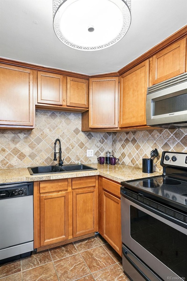 kitchen featuring appliances with stainless steel finishes, a sink, light countertops, and tasteful backsplash