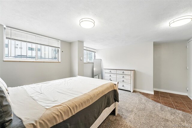 tiled bedroom with a textured ceiling and baseboards
