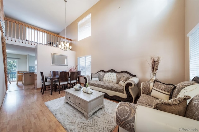 living room featuring a high ceiling, light hardwood / wood-style flooring, and a notable chandelier