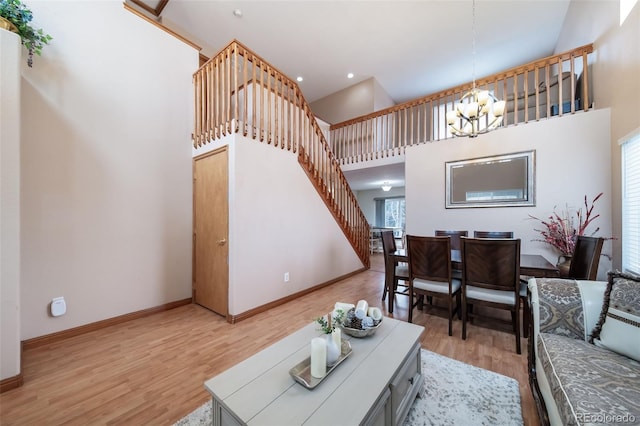 living room with light hardwood / wood-style flooring, a high ceiling, and an inviting chandelier