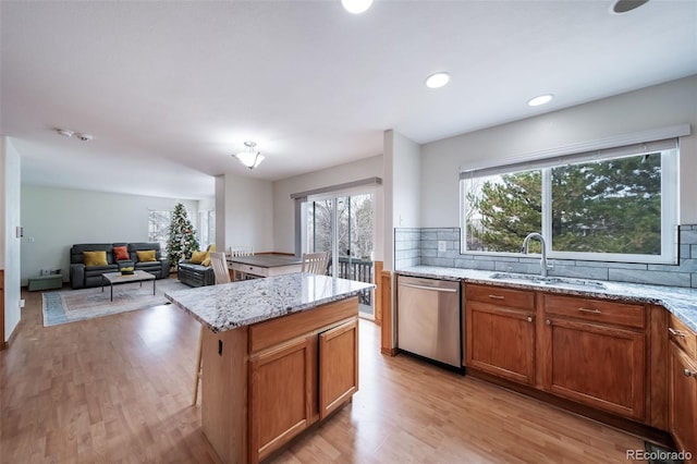 kitchen featuring stainless steel dishwasher, decorative backsplash, a kitchen island, and sink