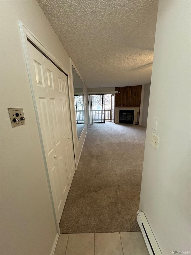 hall with carpet floors, a baseboard radiator, a textured ceiling, and tile patterned floors