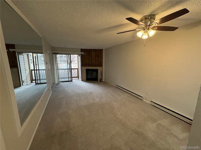 unfurnished living room with a baseboard radiator, light colored carpet, a textured ceiling, and a glass covered fireplace