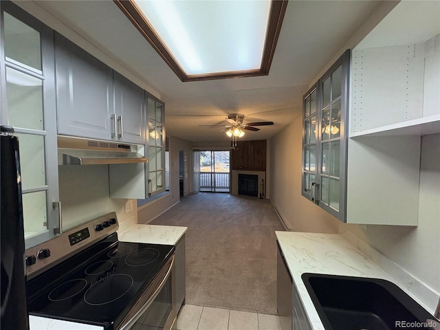 kitchen with light colored carpet, light stone countertops, stainless steel electric range, under cabinet range hood, and a sink