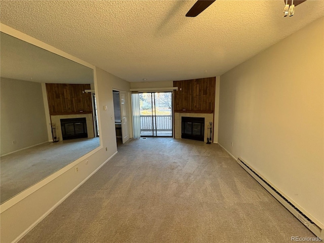 unfurnished living room with baseboards, a baseboard heating unit, light colored carpet, and a glass covered fireplace