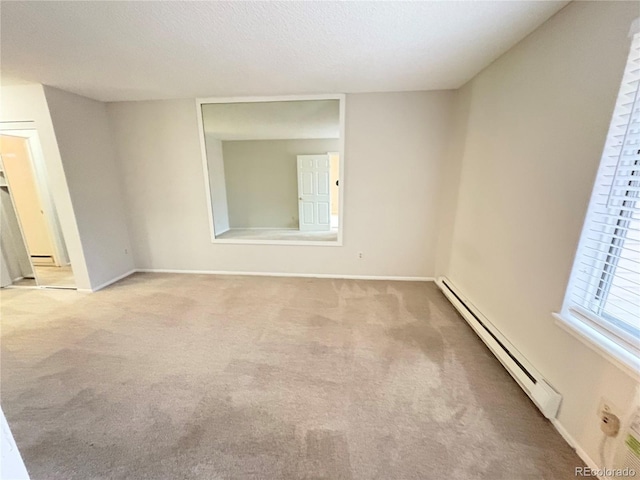 empty room with light carpet, a baseboard radiator, and baseboards