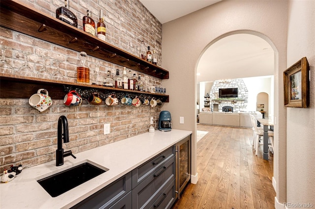 31455 Half Peak Trl, Pine, CO 80470 - bar area featuring a sink, arched walkways, light wood finished floors, wine cooler, and a fireplace