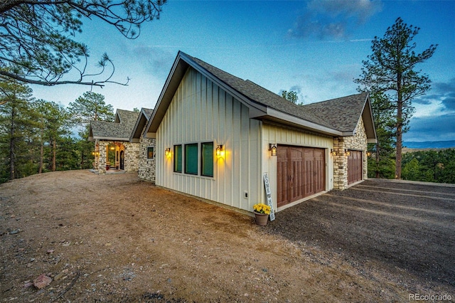 31455 Half Peak Trl, Pine, CO 80470 - view of side of home with board and batten siding, an attached garage, stone siding, dirt driveway, and a shingled roof