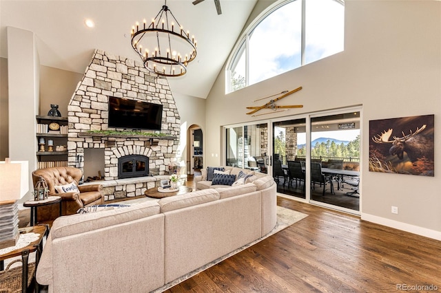 31455 Half Peak Trl, Pine, CO 80470 - living area with arched walkways, a stone fireplace, dark wood finished floors, high vaulted ceiling, and a chandelier