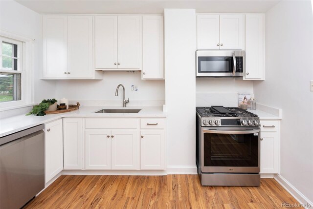 5680 W 41st Ave, Wheat Ridge, CO 80212 - kitchen with appliances with stainless steel finishes, light wood-style flooring, light countertops, and white cabinetry