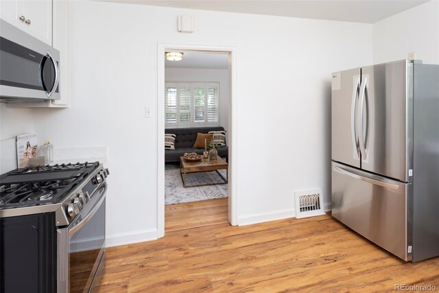 5680 W 41st Ave, Wheat Ridge, CO 80212 - kitchen featuring appliances with stainless steel finishes, light wood-style floors, and white cabinets