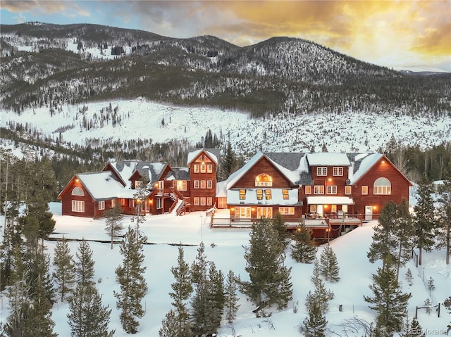 snow covered back of property with a mountain view