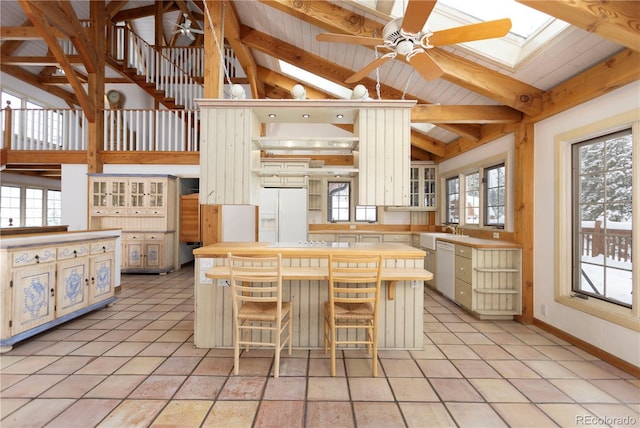 kitchen with vaulted ceiling with skylight, white appliances, ceiling fan, and a sink