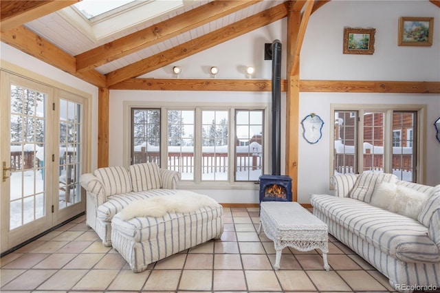 living room featuring vaulted ceiling with skylight, light tile patterned flooring, and a wood stove