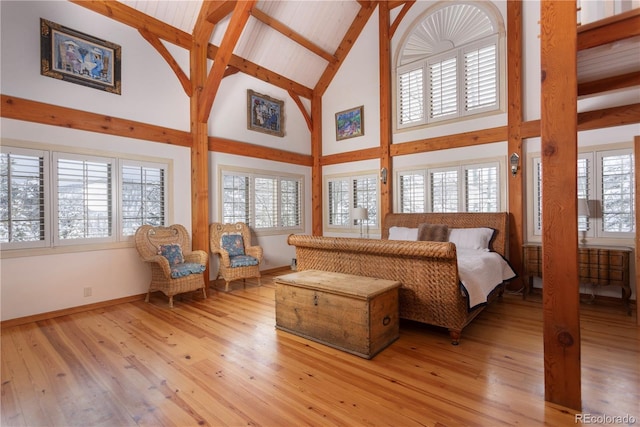 bedroom with high vaulted ceiling, beamed ceiling, light wood-style flooring, and baseboards