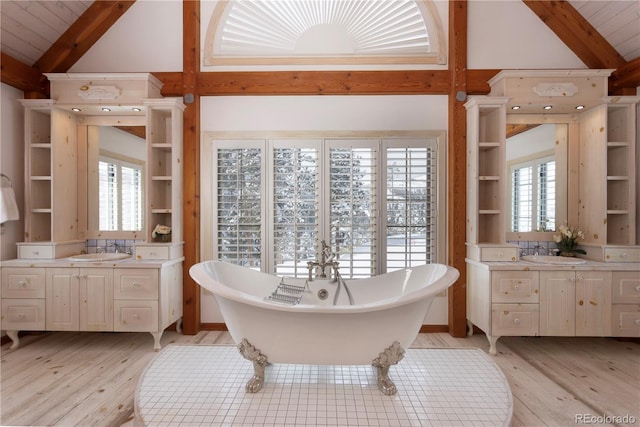 full bath with a sink, hardwood / wood-style flooring, beam ceiling, and a soaking tub