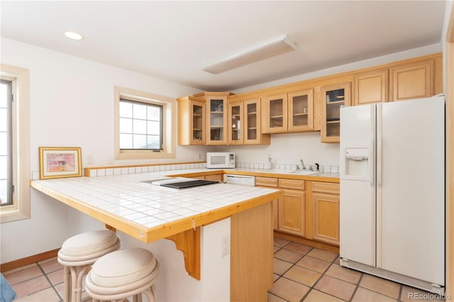 kitchen featuring tile countertops, white appliances, a kitchen bar, and light tile patterned floors