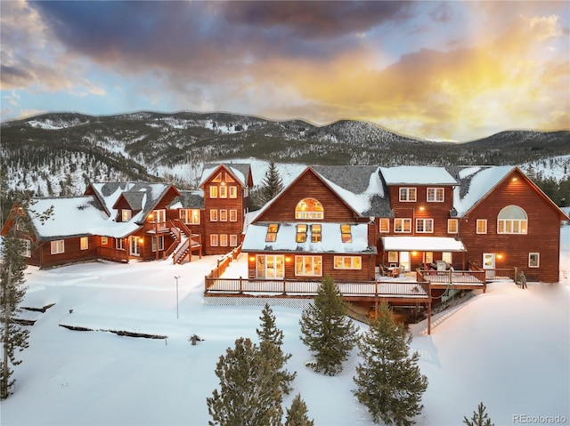 snow covered back of property featuring a deck with mountain view