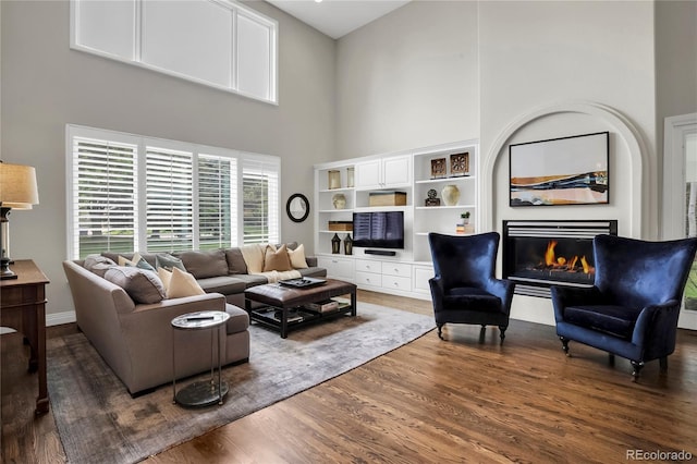 9669 E Prentice Cir, Greenwood Village, CO 80111 - living room featuring a high ceiling, dark wood-style flooring, and a lit fireplace