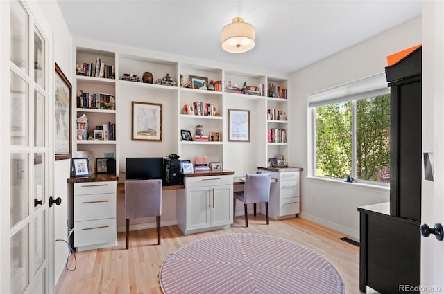 office area with built in study area, light wood-style floors, baseboards, and visible vents