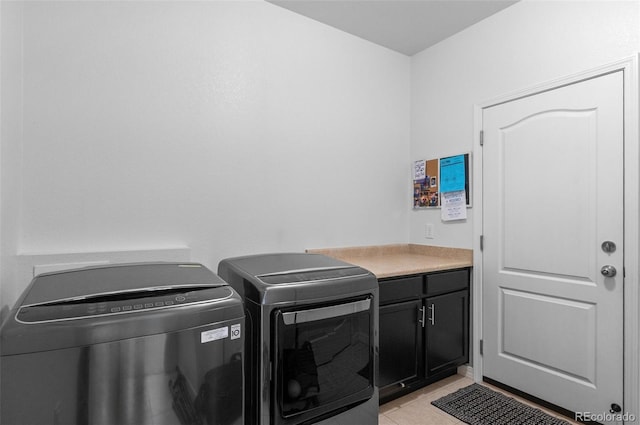 laundry area with cabinet space, washing machine and dryer, and light tile patterned floors
