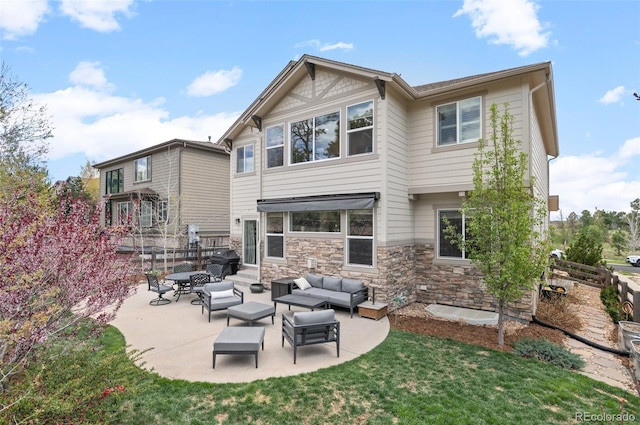 back of property featuring a lawn, fence, an outdoor hangout area, a patio, and stone siding